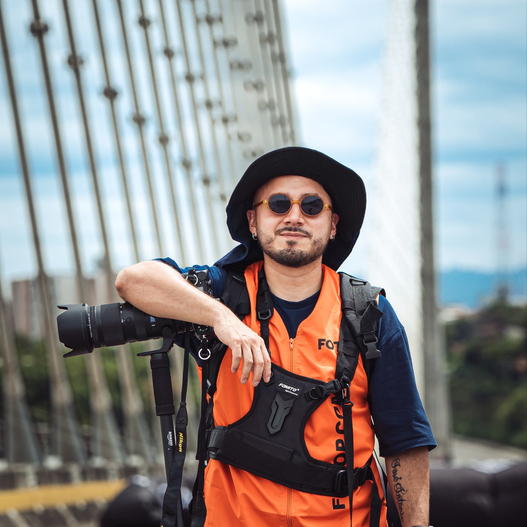Óscar Zárate, fotógrafo deportivo, con su cámara y chaleco de prensa sobre un puente